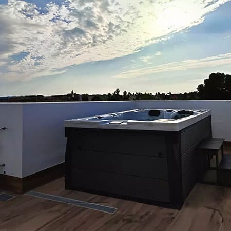 Couple enjoying a 2 person hot tub on a balcony with city skyline