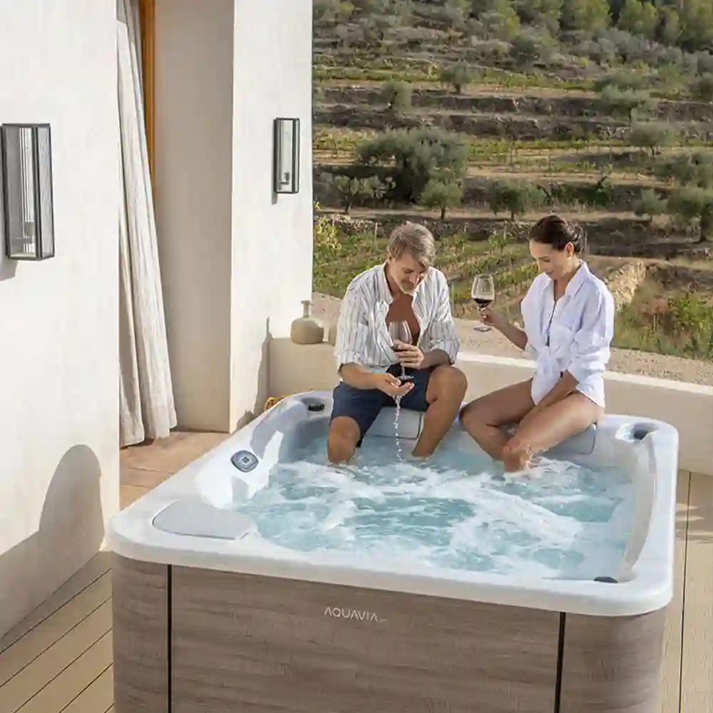 Couple relaxing in an inflatable hot tub on a patio at sunse