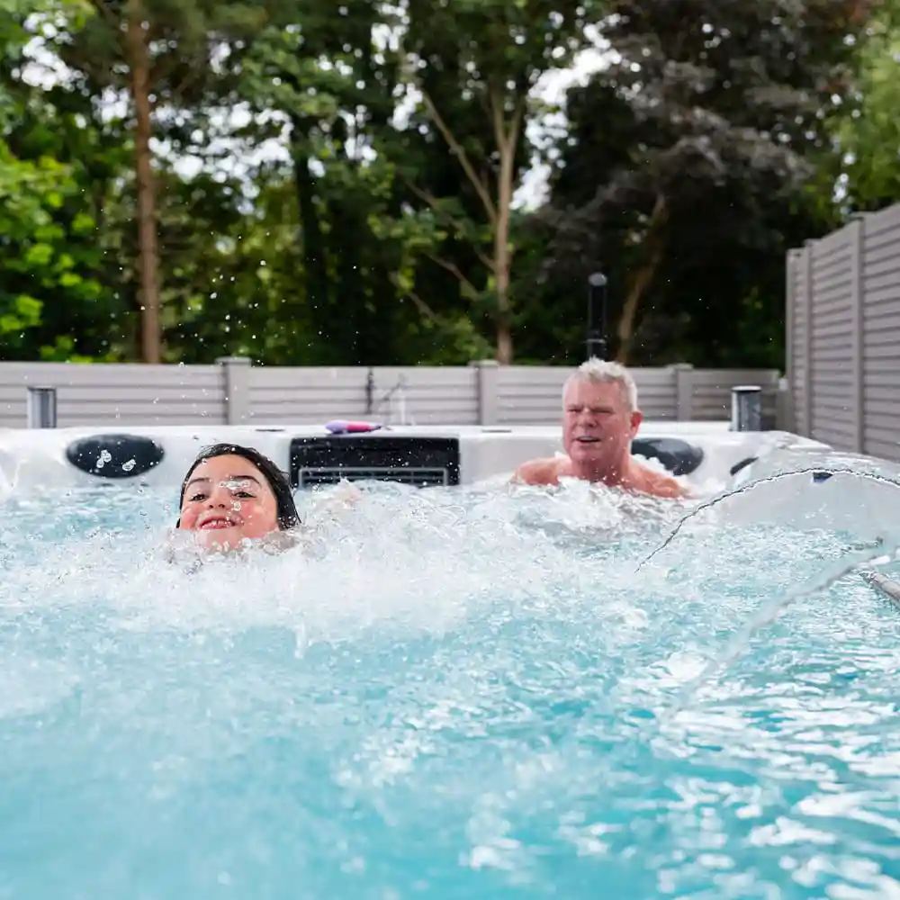 Swim spa with swimmer using resistance current and person relaxing in massage sea