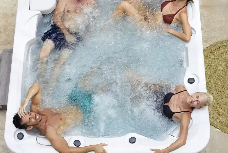 4 people hot tub on a wooden deck with bubbling water and greenery