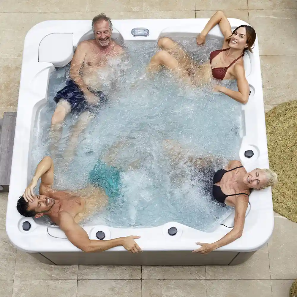 4 people hot tub on a wooden deck with bubbling water and greenery