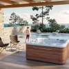 Above ground hot tub installed on a deck with soft lights and greenery