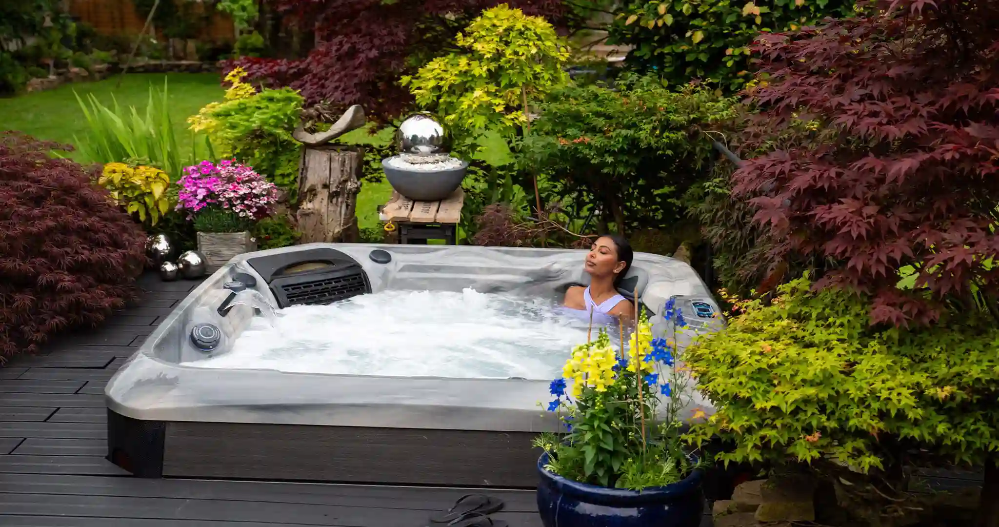Portable hot tub on backyard deck with steam and ambient lighting