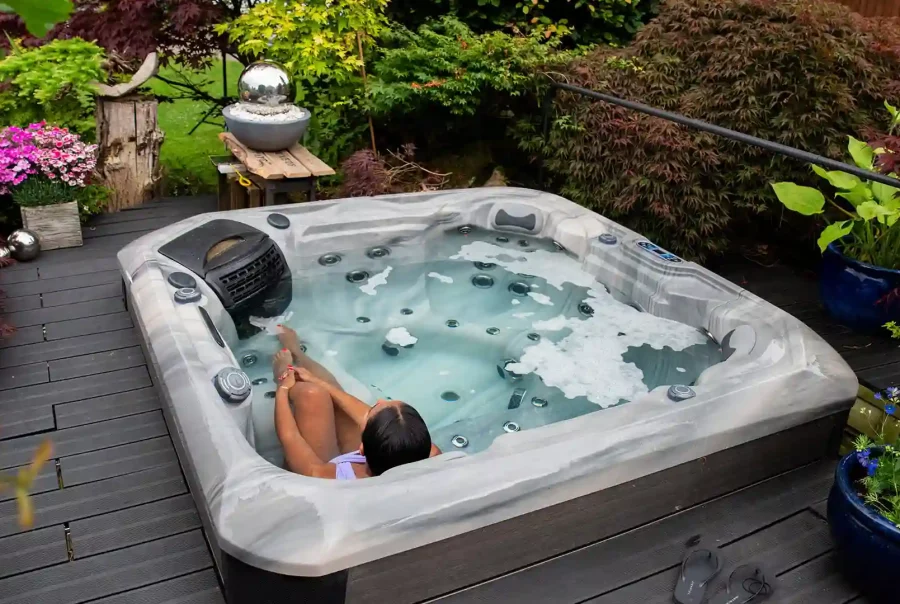 Compact plug and play hot tub on a deck with warm steam and evening lights