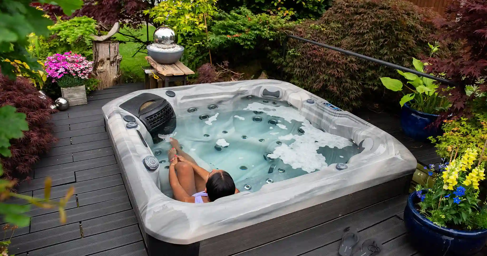 Compact plug and play hot tub on a deck with warm steam and evening lights