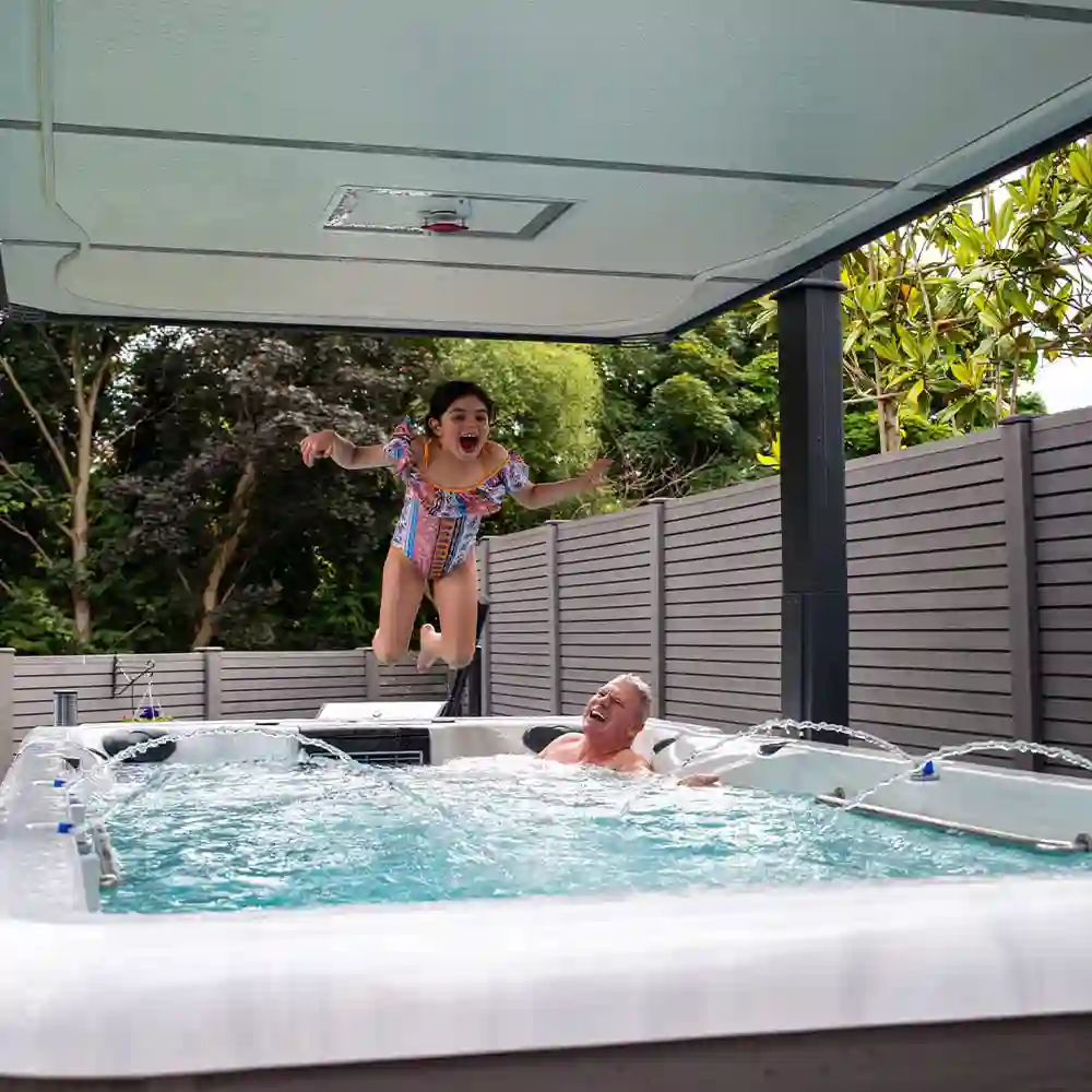 Granddaughter jumping into a swim spa with her grandfather in West Palm Beach, South Florida